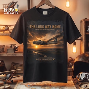 May include: A black t-shirt featuring a graphic print of a vintage bomber aircraft flying over a landscape at sunset. The text reads THE LONG WAY HOME, EVERY MISSION ENDS, NOT EVERYONE RETURNS, AVIATION HERITAGE ARCHIVE, and HEAVY BOMBER COLLECTION.