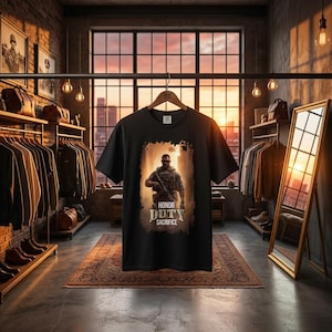 May include: A black short-sleeve t-shirt featuring a graphic print of a soldier in tactical gear holding a rifle. Below the soldier, the text reads HONOR DUTY SACRIFICE in a distressed, weathered font. The shirt is displayed on a wooden hanger.