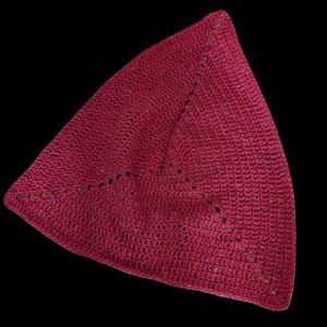 Könnte beinhalten: Burgunderfarbene Häkelmütze mit dreieckiger Form. Die Mütze hat ein strukturiertes Stichmuster und einen dekorativen Rand mit kleinen Ausschnitten. Die Mütze ist aus weichem Garnmaterial gefertigt und eignet sich für Kopfbedeckungen.
