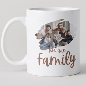 May include: White ceramic mug featuring a family photograph and the copper-coloured text "We are Family". The mug has a large handle and a glossy finish, ideal for tea or coffee.