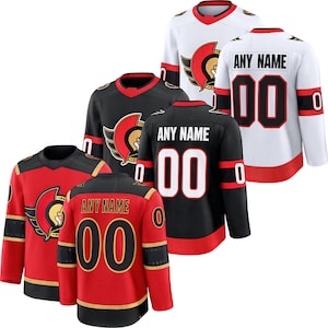 May include: A collection of hockey jerseys in red, black, and white. The jerseys feature the team logo on the front and the option to customize with a name and number on the back. The jerseys have long sleeves and a round neckline.