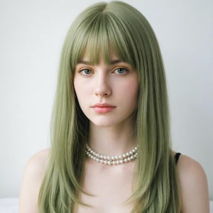May include: A person with long, layered, light green hair with bangs and a double-strand pearl necklace. The person is wearing a black top. The background is a plain white wall.