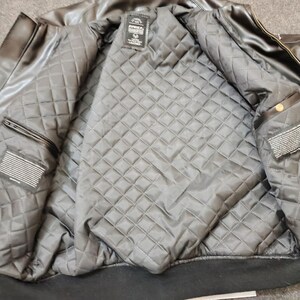 Puede incluir: Chaqueta bomber de cuero negro con forro acolchado con estampado de diamantes. La chaqueta tiene cuello y pu&ntilde;os de canal&eacute; negros e interior negro. La chaqueta tiene una etiqueta que dice "AVIREX".