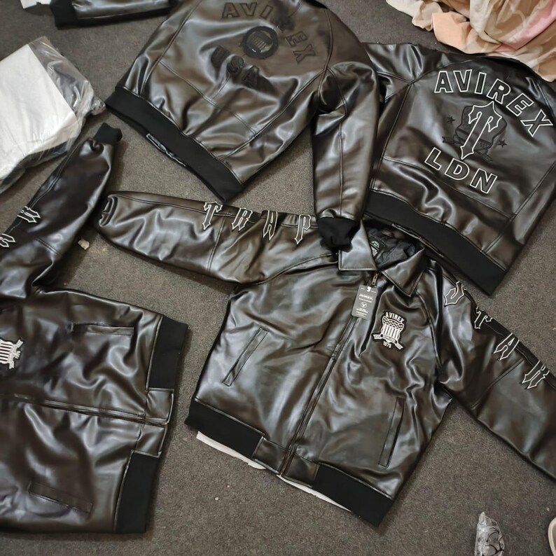 Puede incluir: Varias chaquetas de cuero negro con la marca "Avirex" y "LDN" impresas. Las chaquetas tienen pu&ntilde;os y cuellos de canal&eacute; negros, con detalles bordados blancos en las mangas y la espalda. Algunas chaquetas est&aacute;n con cremallera, otras abiertas.