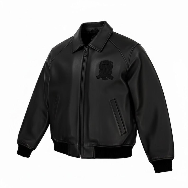 Puede incluir: Chaqueta bomber de cuero negro con cuello, cremallera frontal y un peque&ntilde;o emblema en el pecho. La chaqueta tiene pu&ntilde;os y dobladillo de canal&eacute; negros.