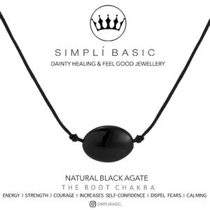 May include: A black agate necklace with a black cord. The necklace features a polished, oval-shaped black stone. The image includes the text "SIMPLÍ BASIC" and "DAINTY HEALING & FEEL GOOD JEWELLERY". The stone is described as "NATURAL BLACK AGATE".