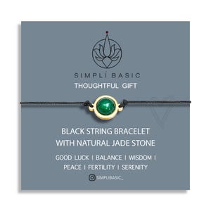 May include: A black string bracelet featuring a natural jade stone in a gold setting. The accompanying card reads "SIMPLI BASIC THOUGHTFUL GIFT" and lists qualities such as "Good Luck" and "Balance".