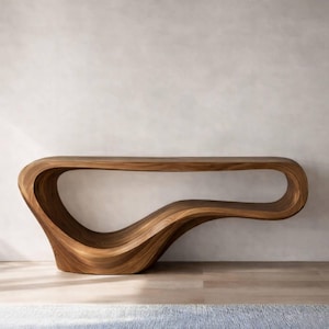 Może przedstawiać: Nowoczesny, rzeźbiarski stolik konsolowy wykonany z drewna o ciepłych odcieniach. Stół ma unikalny, płynny design z zakrzywioną podstawą i długim, otwartym blatem. Widoczne usłojenie drewna dodaje naturalnej estetyki. Stół ma około 183 cm długości.
