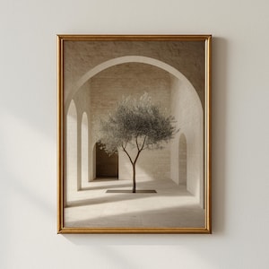 Puede incluir: Una impresión artística enmarcada que presenta una escena interior serena. Un árbol solitario se alza en un pasillo abovedado y soleado con paredes de piedra. La obra de arte está encerrada en un marco dorado, añadiendo un toque de elegancia al diseño minimalista.