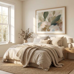 May include: A bedroom interior with a bed dressed in beige linens, a knitted throw, and cushions. Above the bed is a large framed abstract floral painting. A vase with dried branches and a bedside lamp add to the room's decor.
