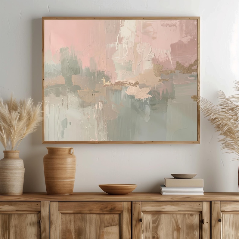 May include: Abstract art print in a wooden frame. The artwork features a blend of pink, beige, and gray brushstrokes with gold accents. The painting is displayed above a wooden cabinet with decorative vases and bowls.