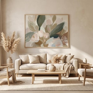 May include: A living room with a large abstract floral painting in a wooden frame above a beige sofa. The room includes wooden chairs, a coffee table, and vases with dried plants, creating a neutral and calming aesthetic.