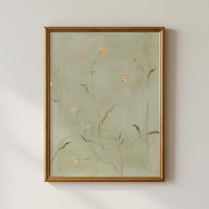 Puede incluir: Una impresión botánica enmarcada con delicadas flores amarillo pálido y hojas verdes sobre un fondo verde suave y apagado. La obra de arte está encerrada en un marco dorado, creando una estética clásica y elegante.