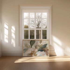 May include: A framed floral art print with a palette of beige, green, and pink. The artwork is displayed on a wooden floor in front of a window with natural light.