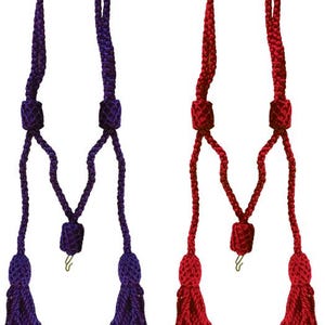 Puede incluir: Dos cordones decorativos con borlas, uno morado oscuro y otro rojo. Cada cordón tiene una parte superior trenzada, un nudo decorativo y una borla. Los cordones son simétricos y cuelgan verticalmente.