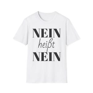 Puede incluir: Camiseta blanca con la frase alemana "NEIN heißt NEIN" impresa en negro. El texto está dispuesto en tres líneas, con "NEIN" arriba y abajo, y "heißt" en el medio, en una fuente de escritura.
