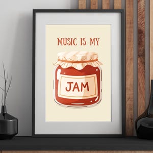 May include: Framed art print featuring a cartoon illustration of a jar of jam. The text "MUSIC IS MY" is above the jar, and "JAM" is written on the jar's label. The artwork is set against a cream background, framed in black.