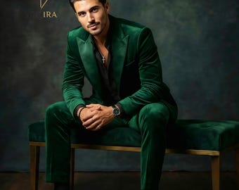 May include: A green velvet suit, including a blazer and trousers, is worn with a black shirt and shoes. The suit is a rich, emerald green color. The person is seated on a green bench with gold legs. A watch and cross necklace are visible.
