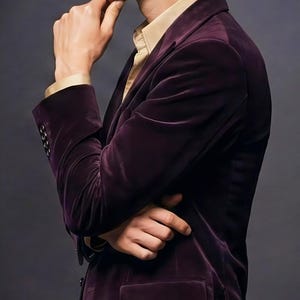 May include: A man in a deep purple velvet blazer with a gold-colored shirt underneath. The word "VEMIRA" is displayed in gold letters at the top of the image. The man is in a thoughtful pose.