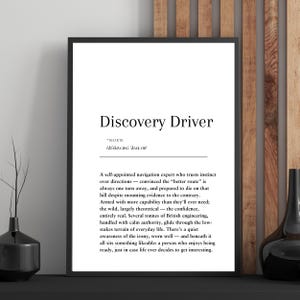 Peut inclure: Impression encadrée en noir avec le texte "Discovery Driver" en noir. Une définition est écrite en dessous. L'impression est affichée sur un mur en bois.