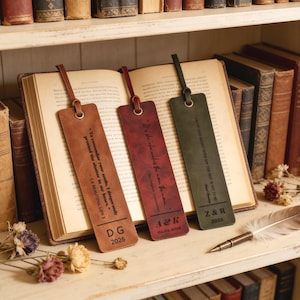 Può includere: Tre segnalibri in pelle marrone, bordeaux e verde, ognuno con una citazione e iniziali. Il marrone recita "To remember your smile..." con "DG 2026". Il bordeaux recita "It's the who make the..." con "A&R 07.02.2026". Il verde recita "Grow old along with me..." con "Z&R 2026".