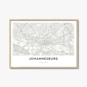 May include: A framed map print of Johannesburg, South Africa, in grayscale. The map details the city's layout, including roads and buildings. The text "JOHANNESBURG SOUTH AFRICA" is centered at the bottom of the print. The frame is a light wood color.