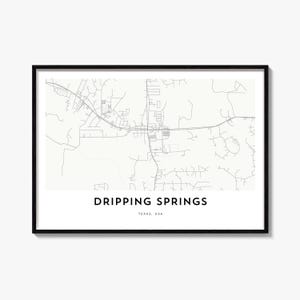 May include: A framed map print featuring a minimalist street layout of Dripping Springs, Texas, USA. The design displays thin gray lines representing roads against a white background, with the text DRIPPING SPRINGS and TEXAS, USA below.