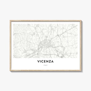 May include: A framed print featuring a detailed map of Vicenza, Italy, in grayscale. The city's name and country are displayed in a clean, modern font below the map. The frame is a light wood color.