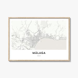 Può includere: Una stampa incorniciata con una mappa dettagliata di Málaga, Spagna, in scala di grigi. Il nome della città è centrato sotto la mappa in grassetto, testo nero, con "SPAIN" sotto. La cornice è di colore legno chiaro.