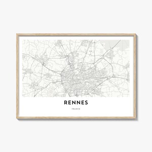 May include: A framed map print of Rennes, France, in grayscale. The city map is detailed, showing streets and buildings. The word "RENNES" is centered at the bottom, with "FRANCE" below it. The frame is a light wood color.