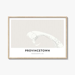 May include: A framed print featuring a map of Provincetown, Massachusetts, USA. The map is in white against a light gray background, with the town's name and location in black text at the bottom. The frame is a light wood color.