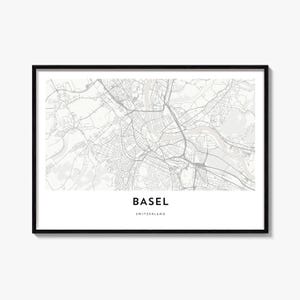 May include: A framed wall art print featuring a detailed grey and white street map of Basel, Switzerland. The map displays intricate road networks and the Rhine river, with the text BASEL and SWITZERLAND printed in black at the bottom center.