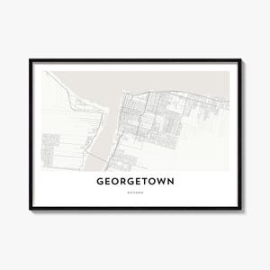 May include: A framed map print of Georgetown, Guyana, featuring a light beige background with grey street grid lines and a water body. The text GEORGETOWN is printed in bold black capital letters, with GUYANA in smaller letters below it.