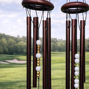May include: Wind chimes with brown tubes, wooden accents, and clear acrylic pendants. One pendant reads "Back Nines Matter Women's League 2026". Other pendants have text that reads "Julie, You are a great golfer..." and a golf course graphic.