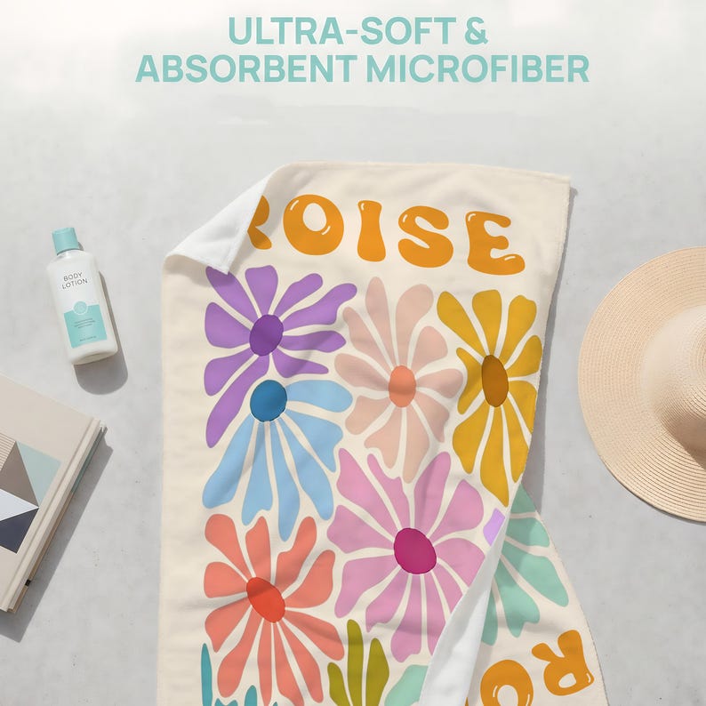 May include: A rectangular microfiber towel featuring a cream-colored background with a repeating pattern of large, stylized flowers in shades of purple, blue, pink, yellow, and orange. The text "OISE" is printed in large, bold, orange letters.
