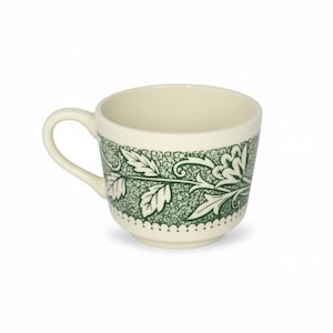 Könnte beinhalten: Cremefarbene Keramik-Teetasse mit grünem Blumenmuster am Rand. Das Design zeigt Blätter und Ranken. Die Tasse hat einen gebogenen Henkel und einen gepunkteten Rand am Boden.