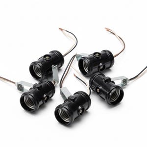 May include: A collection of six black light bulb sockets with silver mounting brackets and attached wires. The sockets are arranged on a white background, showcasing their design and electrical components.