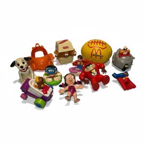 Può includere: Una collezione di colorati giocattoli Happy Meal di McDonald's, tra cui un dalmata, Taz e un pallone da football con il logo McDonald's. Altri giocattoli includono un personaggio in un'auto, un personaggio in barca e un personaggio in una scatola.