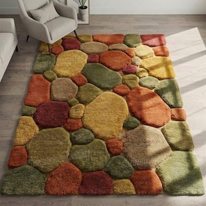 Peut inclure: Un tapis rectangulaire avec un motif de pierres. Le tapis présente diverses couleurs terreuses, notamment des nuances de vert, d'orange, de jaune et de marron. Le design ressemble à un ensemble de pierres de forme irrégulière, créant un aspect texturé.