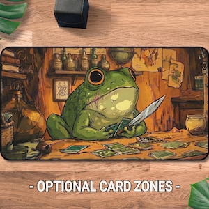 Puede incluir: Una alfombrilla de escritorio rectangular con una rana verde que sostiene un cuchillo sobre una mesa de madera con cartas dispersas. El fondo muestra una habitación con estantes, botellas de vidrio y un insecto enmarcado. Texto: OPTIONAL CARD ZONES.