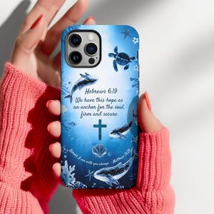 Puede incluir: Una funda de teléfono azul con un diseño oceánico de acuarela que muestra ballenas, una tortuga marina, conchas y coral. El texto dice: Hebrews 6:19 We have this hope as an anchor for the soul, firm and secure, y Behold, I am with you always - Matthew 28:20.