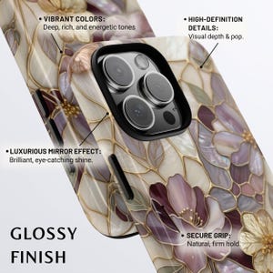 Op de afbeelding: Een smartphonehoesje met een glanzende afwerking en een bloemenpatroon in cr&egrave;me, paarse en gouden tinten. Het ontwerp bevat tekstlabels: VIBRANT COLORS: Deep, rich, and energetic tones, HIGH-DEFINITION DETAILS: Visual depth & pop, LUXURIOUS MIRROR EFFECT: Brilliant, eye-catching shine, en SECURE GRIP: Natural, firm hold.