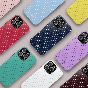 Puede incluir: Una colección de fundas para smartphone en varios colores, incluyendo rojo, azul, amarillo, morado, verde azulado, blanco y marrón oscuro, todas con un patrón de lunares blancos. Varias fundas están personalizadas con monogramas como BR, AS, RP, MR y AK.