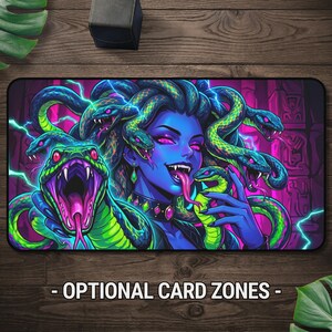 May include: A rectangular playmat featuring a vibrant illustration of a blue-skinned figure with snakes for hair, glowing pink eyes, and sharp fangs. The design includes bright green snakes, electric blue lightning bolts, and a dark purple background.