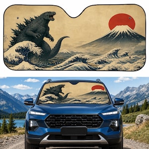 May include: A rectangular car windshield sun shade featuring a graphic illustration of a large grey monster standing in stylized ocean waves next to a snow-capped mountain and a large red sun against a beige background with black trim.