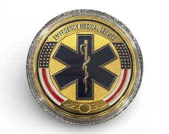 May include: A gold-colored coin with the words "EMERGENCY MEDICAL SERVICE" around the edge. The center features a blue star of life symbol with a gold staff and snake. The coin has red, white, and blue accents and a clear plastic casing.