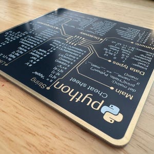 Peut inclure: Une fiche aide-m&eacute;moire Python carr&eacute;e avec une surface noire et du texte blanc. Le design pr&eacute;sente une mise en page technique avec des sections pour les types de donn&eacute;es, les cha&icirc;nes, les listes et les fonctions principales, incluant le logo Python.