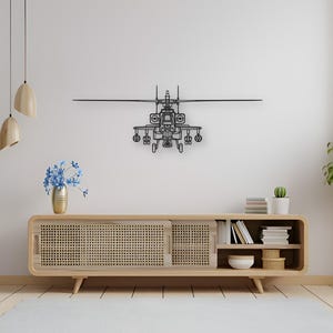 May include: A black metal helicopter wall art piece is mounted on a white wall. The artwork is a detailed silhouette of a helicopter. The room also features a wooden cabinet, a rug, and decorative plants.