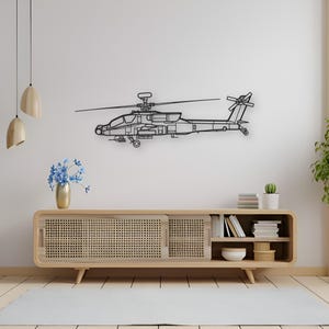 May include: Black metal helicopter wall art. The detailed outline of the aircraft is mounted on a white wall above a wooden cabinet. The cabinet has a woven front and open shelves with books and decor.