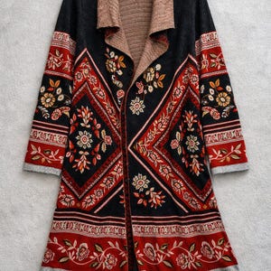 Könnte beinhalten: Langer Cardigan mit offenem Schnitt und floralem Muster. Der Pullover hat einen schwarzen Körper mit roten und cremefarbenen Blumendesigns. Der Kragen ist hellbraun, und die Ärmel und der Saum haben einen grauen Rand.